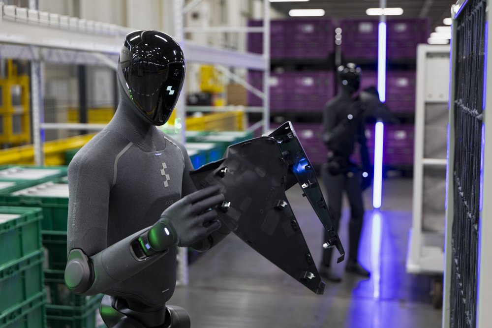 Two Figure 03 humanoid robots handling parts on BMW's Spartanburg production floor