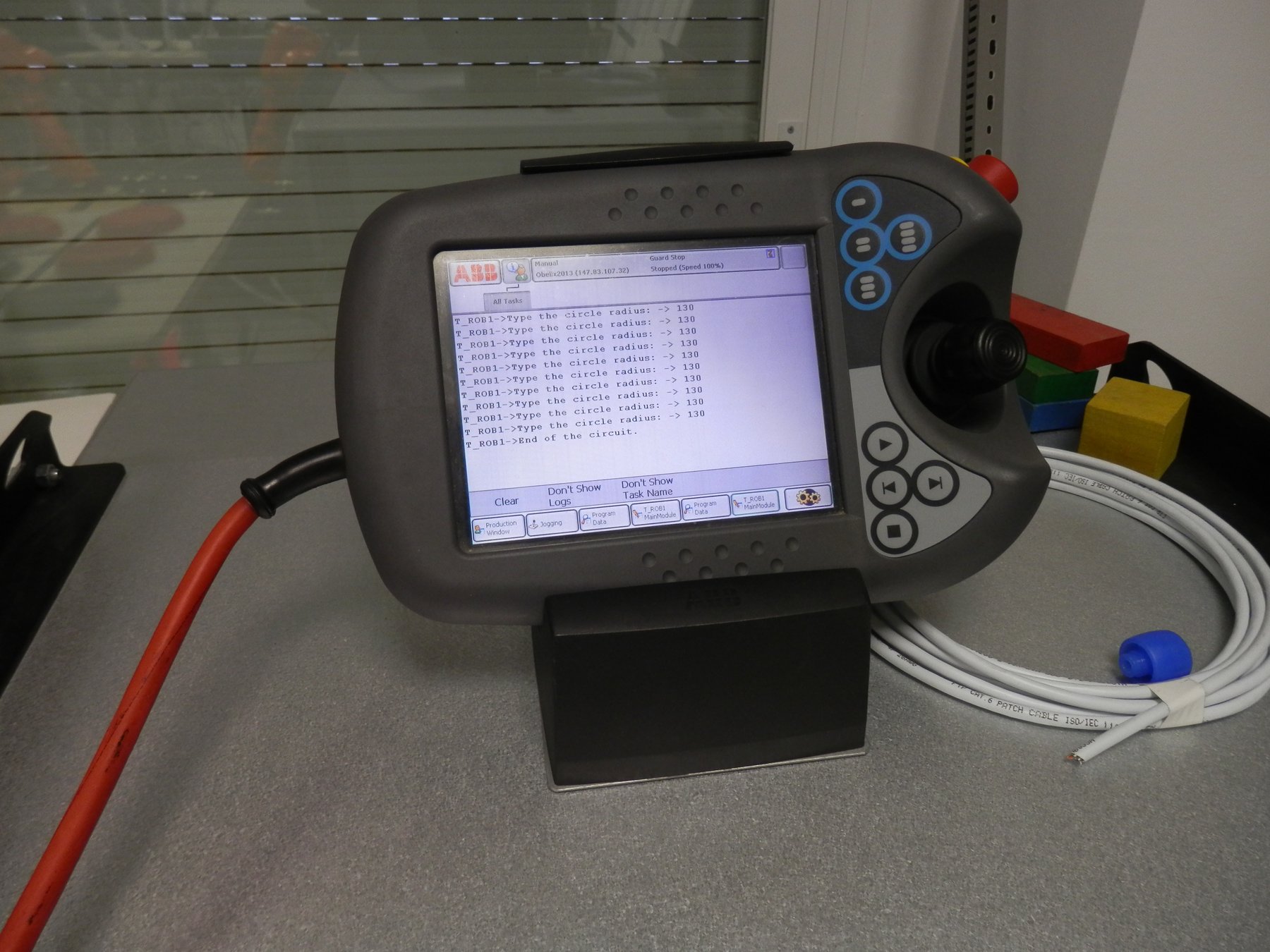 プログラム実行画面が表示されたABB製IRB140用ティーチペンダントのクローズアップ
